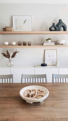 a bowl filled with mushrooms sitting on top of a wooden table next to a shelf