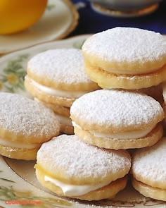 a pile of powdered sugar cookies on a plate with lemons in the background