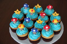 cupcakes with blue frosting and mario bros decorations on top are arranged on a plate