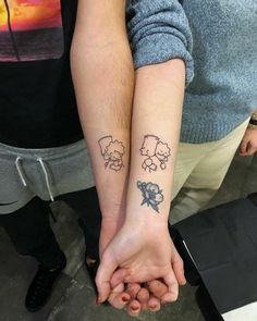 two people holding hands with tattoos on them