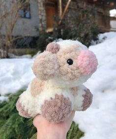 a hand holding a small stuffed animal in the snow