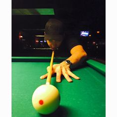 a person leaning over a pool table with a ball and cue in their hand,