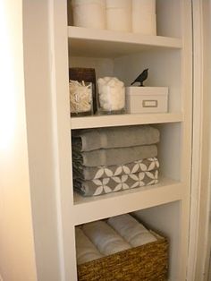 the shelves in this bathroom are filled with folded towels and other things to put on them