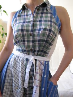 a woman wearing a plaid dress standing in front of a window with her hands on her hips