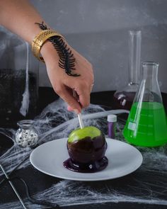 a person is decorating an apple with purple liquid and spooky spider web