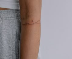 a woman's arm with a small wave tattoo on the left side of her arm