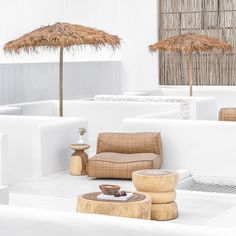 an outdoor seating area with straw umbrellas on the roof and chairs in the background