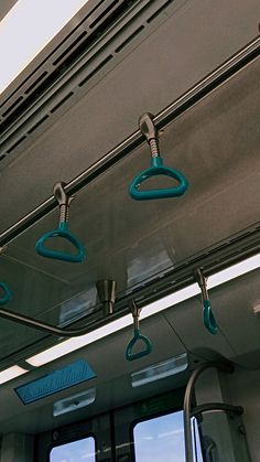 the inside of a bus with blue handles and hooks hanging from it's ceiling