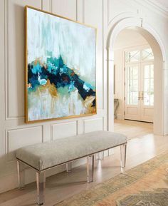 a large painting hanging on the wall above a bench in a room with white walls