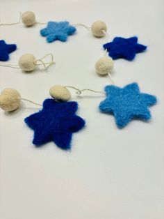 blue and white felt stars are hanging from strings on the table with balls attached to them