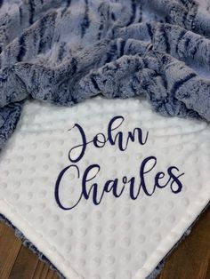 a blanket with the word john charles written on it, laying on top of a wooden floor