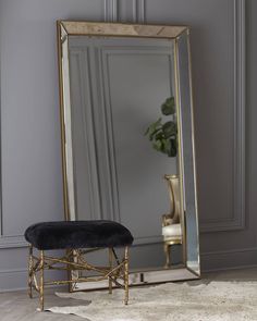 a mirror sitting on top of a wooden floor next to a chair and potted plant