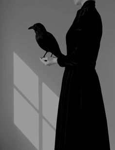 a black and white photo of a woman in a dress holding a bird on her hand