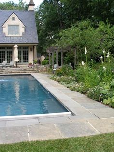 a house with a pool in the front yard and landscaping around it, along with an outdoor dining area