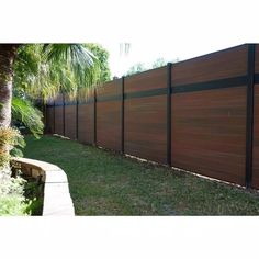 a wooden fence in front of a palm tree on the side of a house with grass