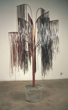 a sculpture made out of metal rods on top of a cement floor next to a white wall