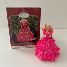 a barbie doll in a pink dress next to a christmas ornament and box