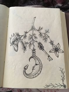 an open book with drawings on it and a key hanging from the tree branch in the middle