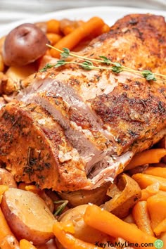 a white plate topped with meat, potatoes and carrots next to an olive sprig