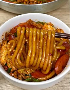 two bowls filled with food and chopsticks on top of the bowl, next to each other