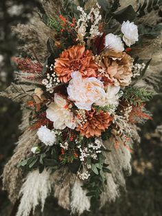 an arrangement of flowers and foliage is hanging from the ceiling