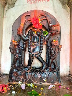 a statue with flowers on it in front of a wall