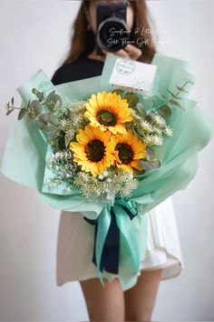 a woman holding a bouquet of sunflowers in front of her face while taking a selfie