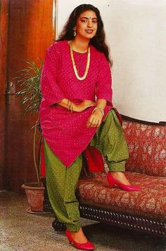 a woman sitting on top of a couch next to a potted plant