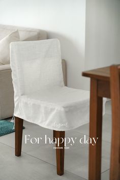 a white chair sitting next to a wooden table in front of a couch with the words for happy day written on it