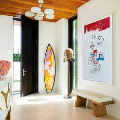 a room with a surfboard on the wall and a painting hanging in front of it