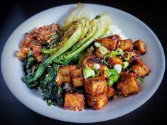 a white plate topped with tofu and vegetables