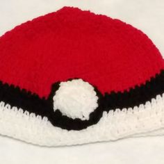 a crocheted hat with a black and white ball on it's side