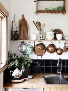 a kitchen with pots and pans on the shelves above the sink, next to an oven