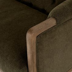 a close up view of the arm and back of a green couch with wood trim