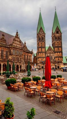 an outdoor dining area with tables and chairs in front of large cathedral - like buildings