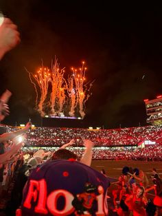 fireworks are lit up in the sky above a stadium full of people and fans at a football game