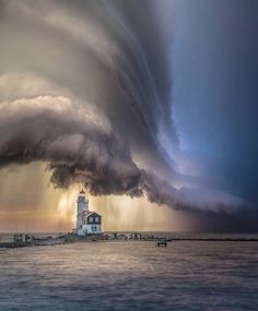 a large cloud is above a lighthouse in the ocean