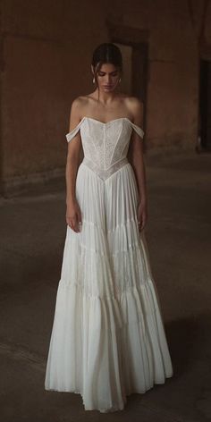 a woman wearing a white dress standing in an empty room