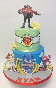 a three tiered cake with sonic the hedgehog figurine on top and other characters around it