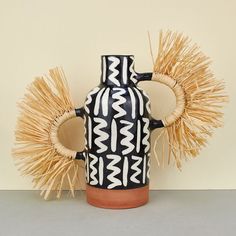 a black and white vase sitting on top of a table next to two straws