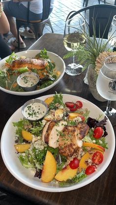 two white plates filled with food on top of a table next to glasses of wine