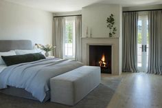 a bedroom with a bed, fireplace and large windows