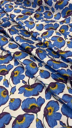 blue flowers on white fabric with yellow centers and dark purple centers, as well as an orange center