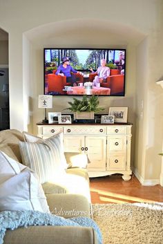 a flat screen tv mounted to the side of a wall next to a couch and coffee table