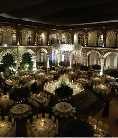 an indoor venue with tables, chairs and chandeliers in the center is lit up at night