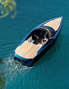 a small blue boat in the middle of the water with a wooden deck on it's side