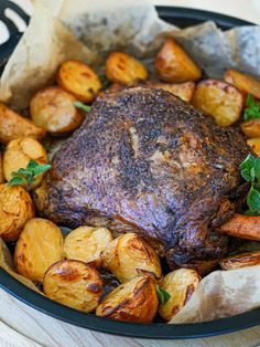 a roasting pan with potatoes and meat in it