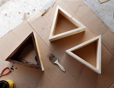 three pieces of wood sitting on top of a cardboard box next to a paintbrush