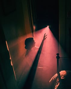 a person standing in the dark with their arm raised up and light coming from behind them