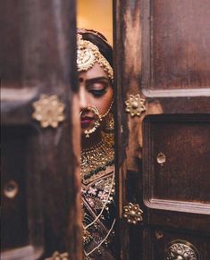 an arabic woman in traditional dress peeking out from behind a door with the words, she is